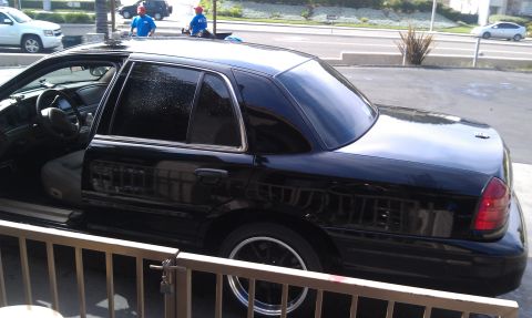 2003 Ford Crown Victoria - Glossy black four-door sedan in profile with dark tint parked at a detail bay