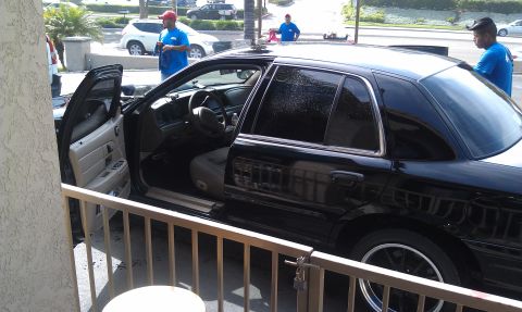 2003 Ford Crown Victoria - Open-door view of a black sedan's tan cabin as attendants work nearby