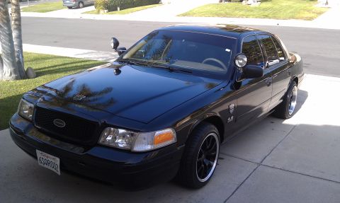 2003 Ford Crown Victoria - Front quarter of a dark Crown Victoria on a driveway, blacked grille and amber turn signals