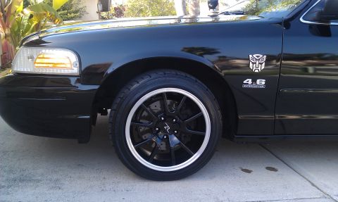 2003 Ford Crown Victoria - Detail of black Crown Victoria front wheel and fender with 4.6 Interceptor badge and Transformers logo