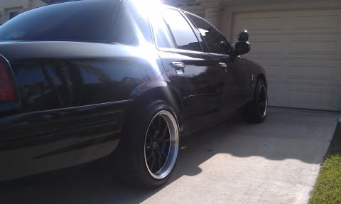 2003 Ford Crown Victoria - Low-angle side shot of a black Crown Victoria, black machined-lip wheels and dark tint