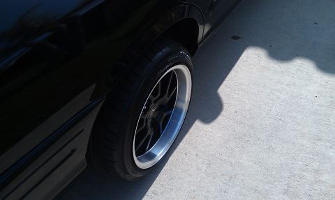 2003 Ford Crown Victoria - Ground-level view of a black Crown Victoria front wheel and rocker on a concrete driveway