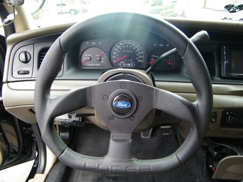 2003 Ford Crown Victoria - Black perforated Corsa steering wheel with Ford emblem in front of a Crown Victoria gauge cluster