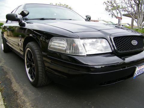 2003 Ford Crown Victoria - Front three-quarter of a black Crown Victoria, clear corner lenses and black machined-lip wheel