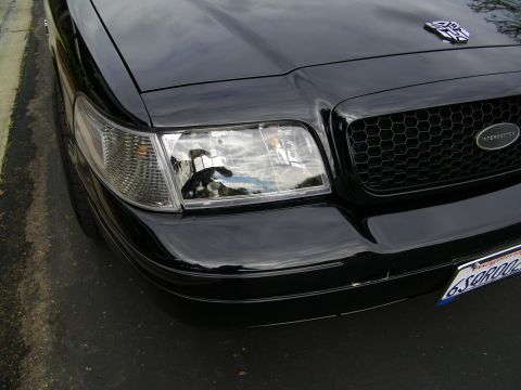 2003 Ford Crown Victoria - Detail of black Crown Victoria headlight and honeycomb grille marked Interceptor, plate 6S9R002