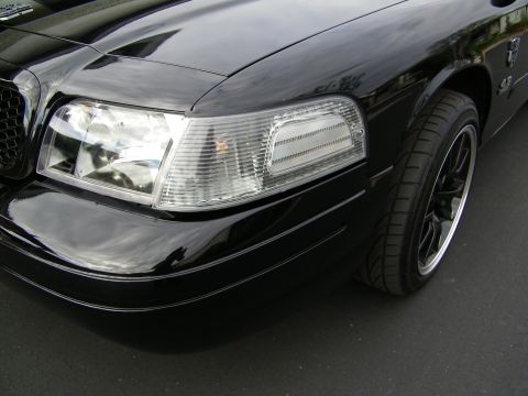 2003 Ford Crown Victoria - Detailed front-corner shot of a glossy black Crown Victoria with clear headlight lens