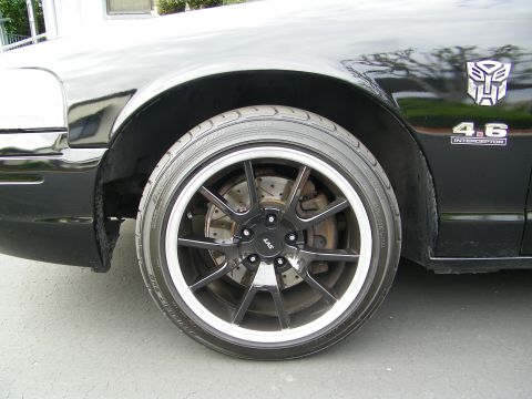 2003 Ford Crown Victoria - Black multi-spoke wheel and brake on a Crown Victoria fender bearing 4.6 Interceptor badge