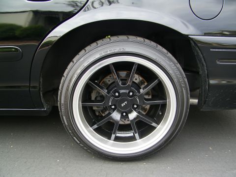 2003 Ford Crown Victoria - Close-up of an SVT-logo black multi-spoke wheel and brake rotor mounted on a black car