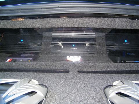 2003 Ford Crown Victoria - Row of Alpine amps and a bass processor on a trunk panel above silver subwoofers