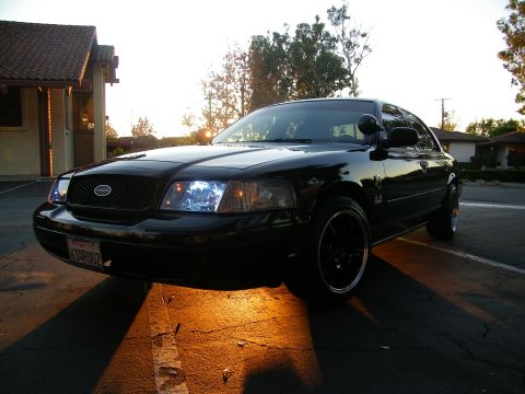 2003 Ford Crown Victoria - Low sun behind a black Crown Victoria showing dark wheels and front-quarter profile