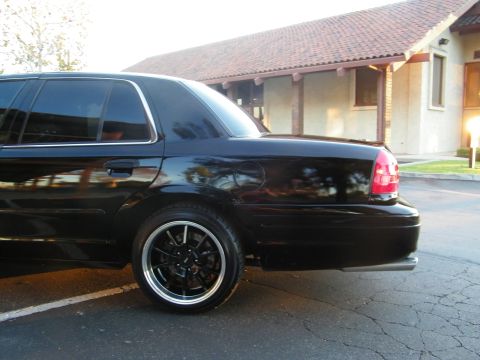2003 Ford Crown Victoria - Close rear-corner view of a black Crown Victoria showing dark wheel and body line