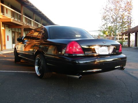 2003 Ford Crown Victoria - Black Crown Victoria rear-quarter view with twin exhaust tips in a motel parking lot