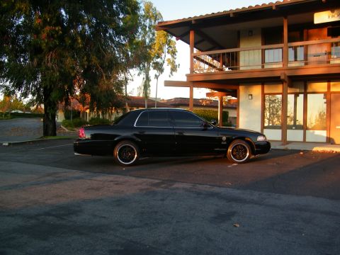 2003 Ford Crown Victoria - Full side profile of a lowered black Crown Victoria at sunset beside a balconied building.