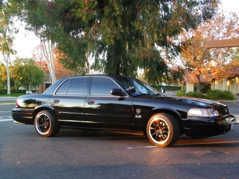 2003 Ford Crown Victoria - Black Crown Victoria sedan at golden hour, headlights and reflections off the glossy paint.