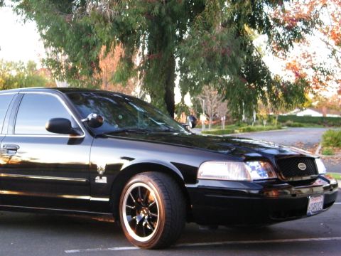 2003 Ford Crown Victoria - Low front-corner view of a black Crown Victoria with glossy paint and black staggered wheel.
