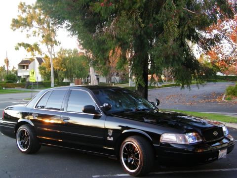 2003 Ford Crown Victoria - Black Crown Victoria parked at a residential curb at dusk, school-zone sign behind.