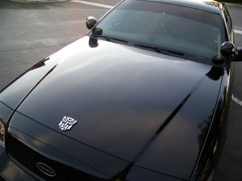 2003 Ford Crown Victoria - High-angle of a dark Crown Victoria hood bearing a white Autobot decal near the grille.