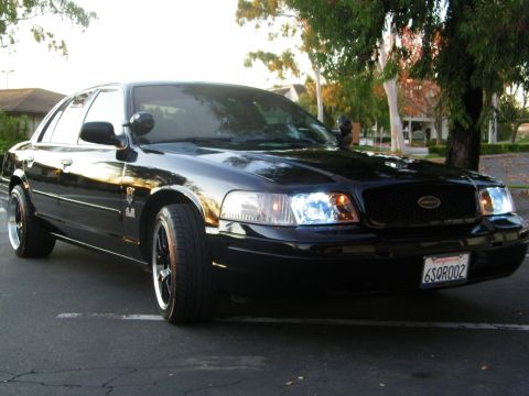 2003 Ford Crown Victoria - Close front-quarter view of a black Ford sedan with 4.6 fender emblem and dark grille.