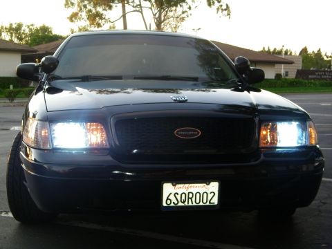 2003 Ford Crown Victoria - Head-on front view showing the Ford oval and INTERCEPTOR grille lettering of a black sedan.