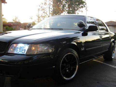 2003 Ford Crown Victoria - Close front-quarter view of a black Ford sedan showing the 4.6 fender emblem.