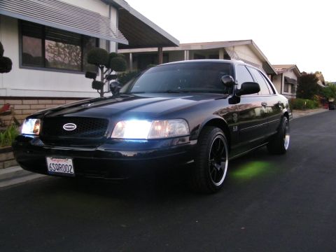 2003 Ford Crown Victoria - Black Ford sedan with green underglow parked along a residential driveway at dusk.