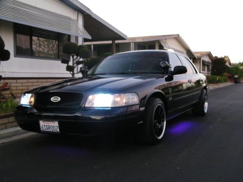 2003 Ford Crown Victoria - Front-quarter view of a black Ford sedan lit with purple underbody LEDs at twilight.