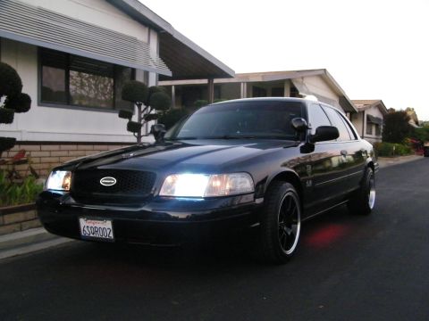 2003 Ford Crown Victoria - Black Ford sedan with red underbody lighting parked along a residential street.