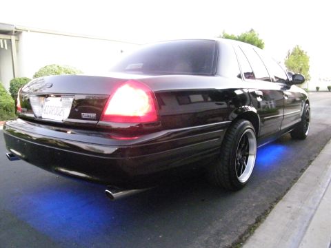 2003 Ford Crown Victoria - Rear-quarter shot of a black Ford sedan glowing blue underneath with dual exhaust.