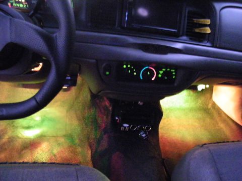 2003 Ford Crown Victoria - Green-orange footwell LEDs light a Ford sedan's interior carpet with bright dash and climate displays.