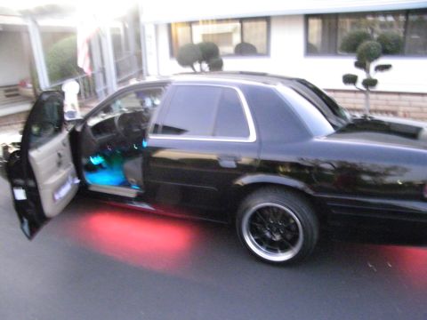 2003 Ford Crown Victoria - Side view of a black Ford full-size sedan with door open, lit interior and red underglow, on a driveway.