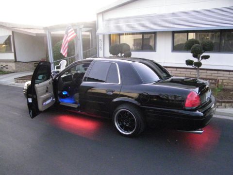 2003 Ford Crown Victoria - Lowered black Crown Victoria parked by a building, driver door open showing blue interior and red underbody LEDs