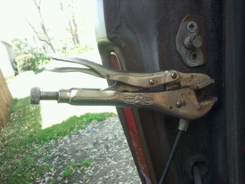 1979 Ford Bronco - Locking pliers are attached to the door latch of a vehicle.