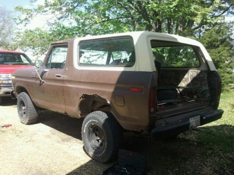 1979 Ford Bronco - This Ford Bronco is seen from the rear, with its tailgate open, parked next to a red truck.