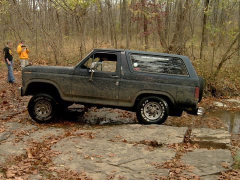 1982 Ford Bronco - This Ford Bronco is navigating a rocky stream bed in a forest setting.