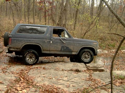 1982 Ford Bronco - This 1982 Ford Bronco navigates a rocky trail through a forest with fallen leaves on the ground.