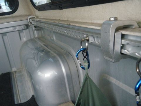 2003 Nissan Frontier - Interior view of a truck bed showing a metal tie-down track system with carabiners attached.
