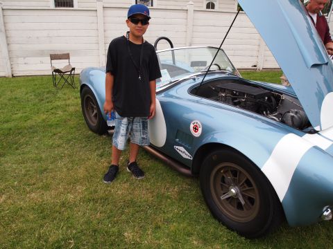 1994 Ford Bronco - A boy poses with a classic AC Cobra replica, its hood open to reveal the engine.