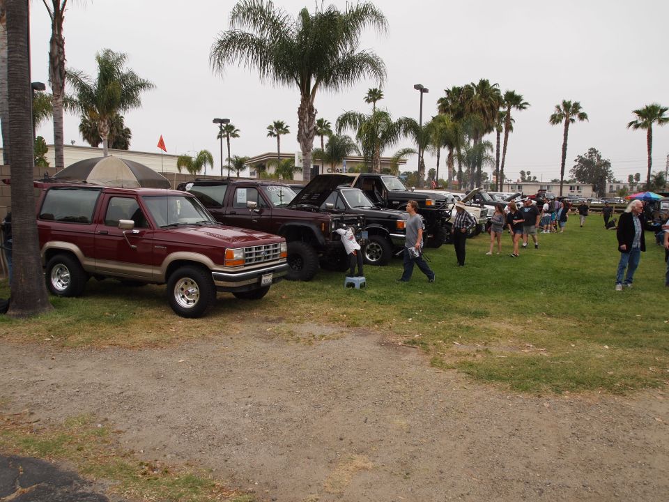 Maroon Ford Bronco II parked on gravel, tan lower body trim, chrome wheels, side view