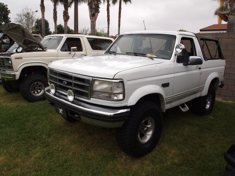 1994 Ford Bronco - A white 1994 Ford Bronco is parked on grass, with another Bronco visible behind it.
