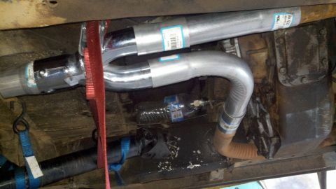 1978 Ford Bronco - The underside of a vehicle shows a new exhaust system and transmission components, secured with straps.