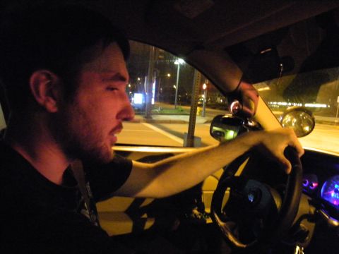 2003 Ford Crown Victoria - Nighttime interior shot of a male driver gripping the wheel with city lights through windshield