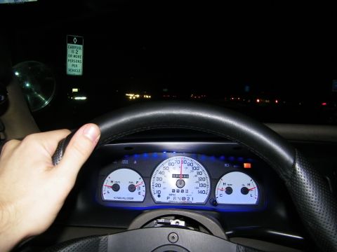 2003 Ford Crown Victoria - Night driving view, hand on wheel, blue-lit dash, green carpool sign reading 2 or more persons