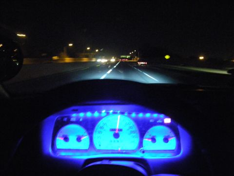 2003 Ford Crown Victoria - Dark freeway ahead with oncoming lights and blue-lit dashboard gauges in foreground