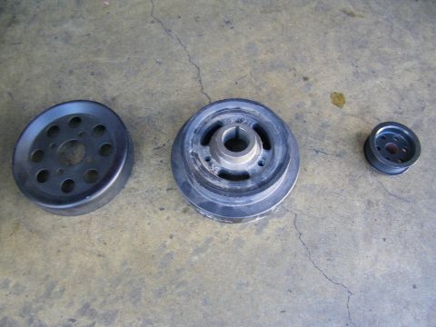 2003 Ford Crown Victoria - Set of automotive pulleys including a harmonic balancer arranged on garage floor