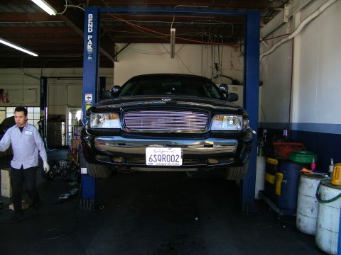 2003 Ford Crown Victoria - Front view of black full-size sedan elevated on a BendPak lift in a repair shop