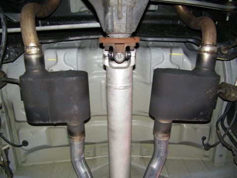 2003 Ford Crown Victoria - Center driveshaft U-joint flanked by twin exhaust mufflers under a lifted vehicle