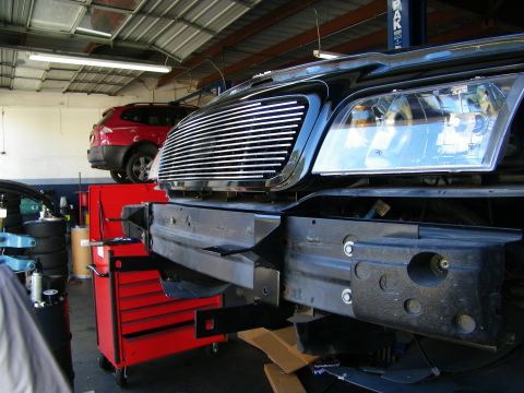 2003 Ford Crown Victoria - Black truck front with billet grille on a lift, bumper removed to expose the core support