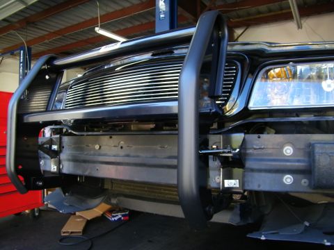2003 Ford Crown Victoria - Shop view of an installed black brush guard over a billet grille, headlight and frame exposed during fitment