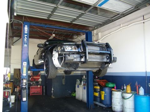 2003 Ford Crown Victoria - Vehicle hoisted on a BendPak lift, front bumper cover off exposing radiator support and grille guard