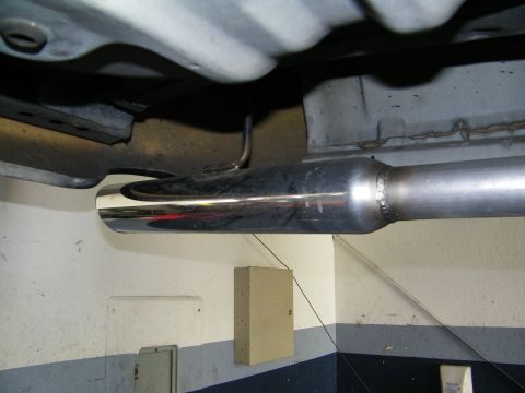2003 Ford Crown Victoria - Polished angle-cut exhaust tip on a muffler installed beneath the vehicle against a blue shop wall